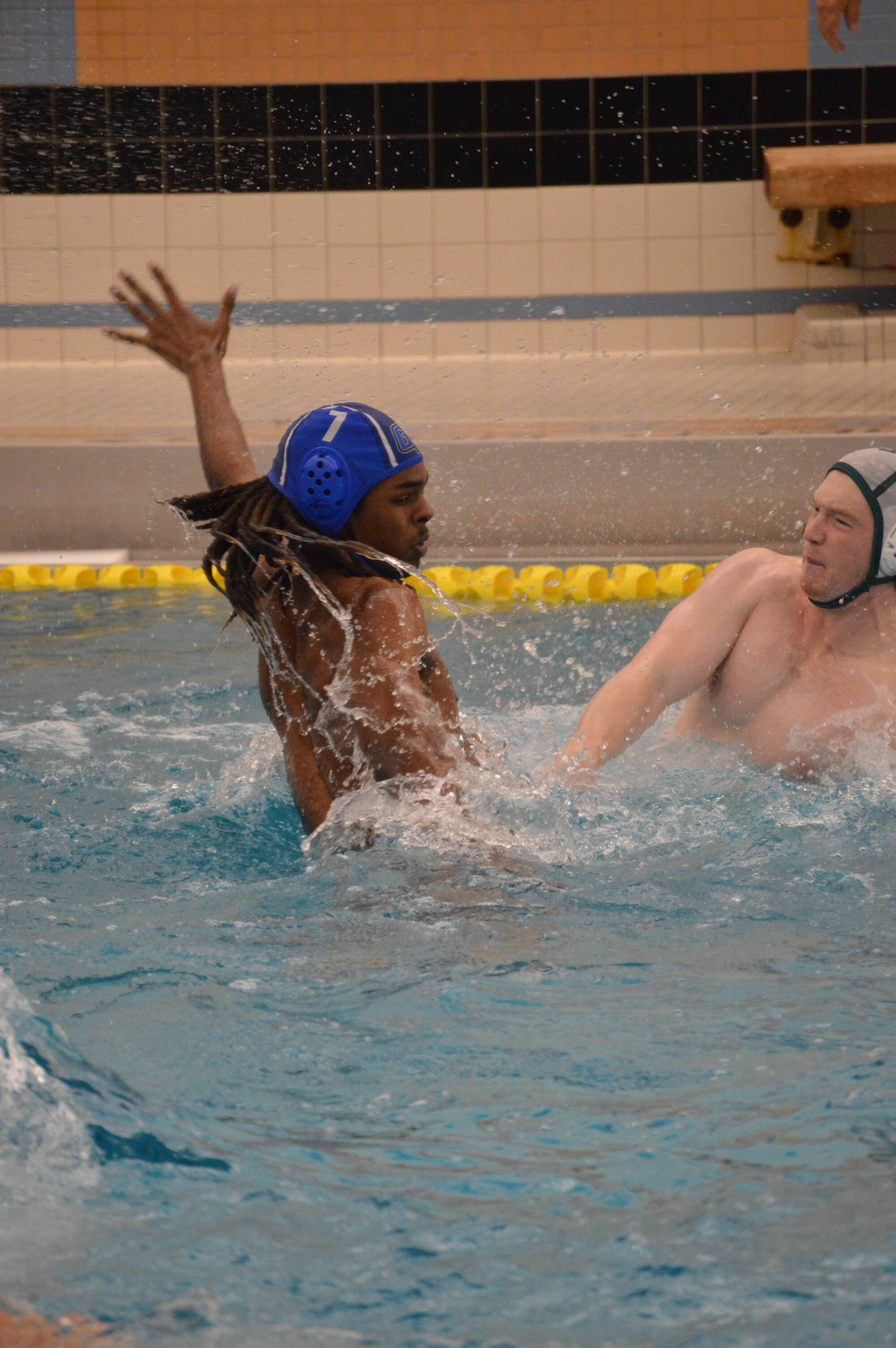 Water polo player (7) with arm up defending opponent.
